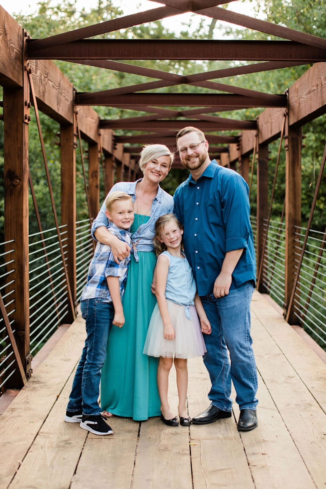 A family of four photographed together on a footbridge